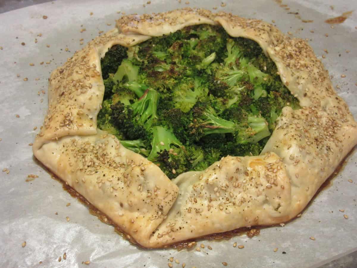 A baked broccoli crostata with sesame seeds around the sides.