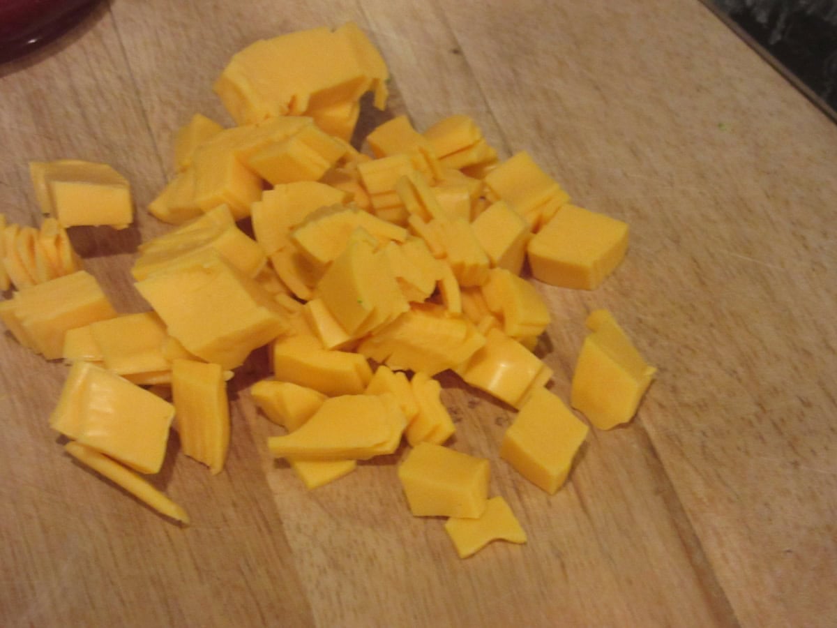 Diced American cheese on a wooden cutting board.