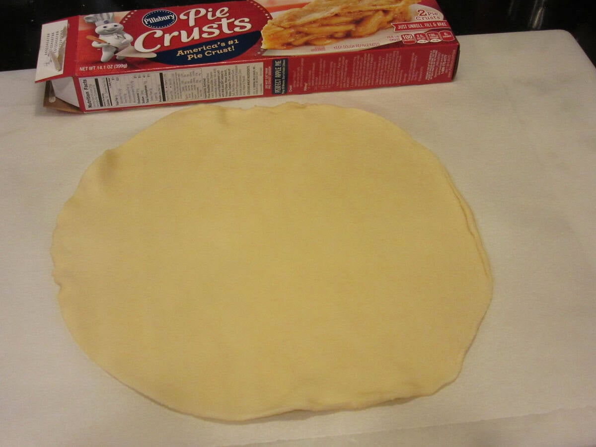 A round dough of prepared pie crust on a counter top with the pie crust box in the background.