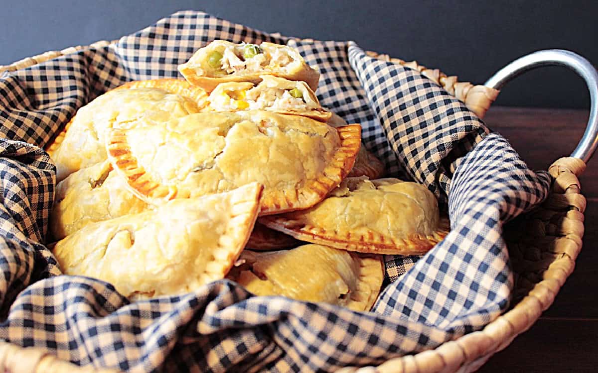 A basket filled with golden brown chicken pot pie pockets made using store-bought pie crust.