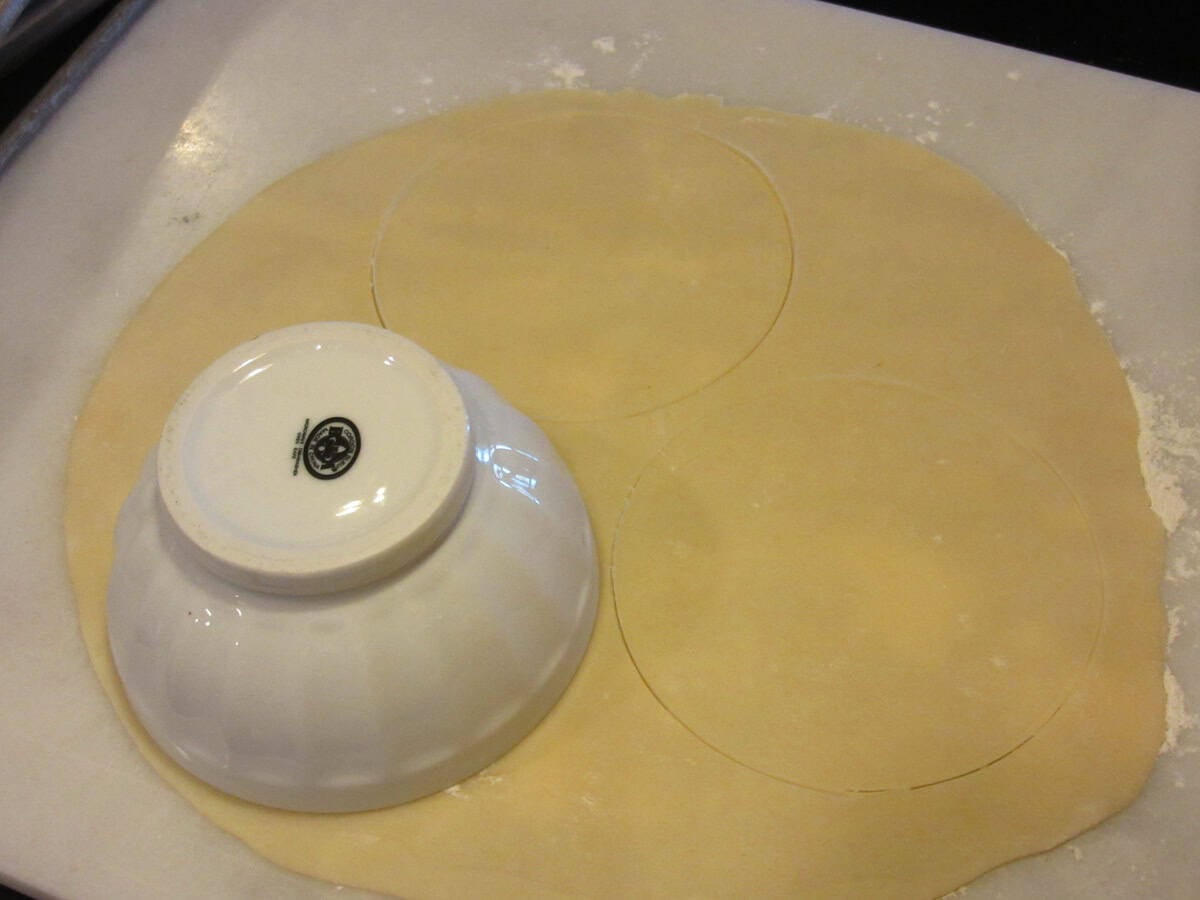 A small bowl sitting on piecrust as a template for cutting circles.