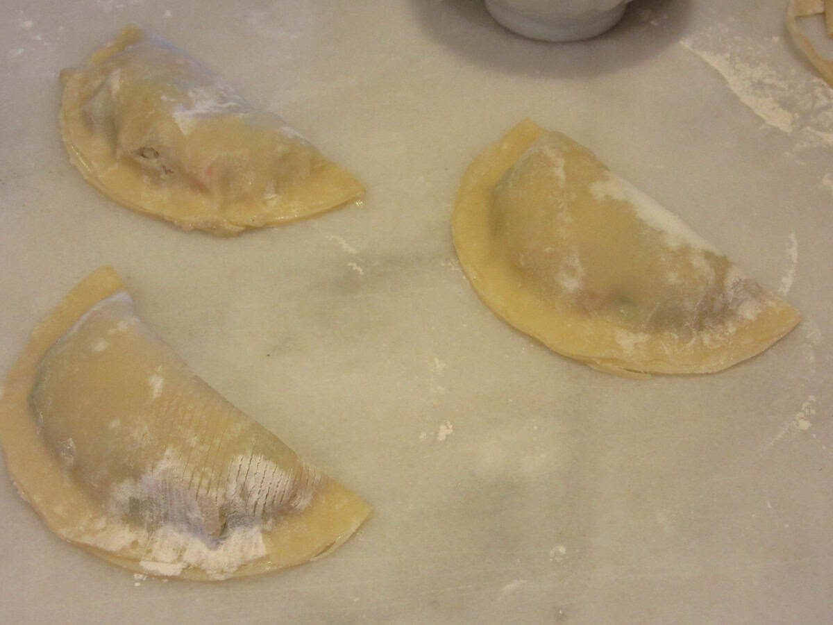 Three folded over chicken pot pie pockets on a floured surface.