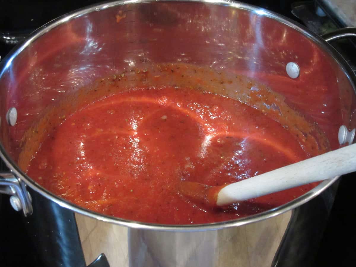 A large saucepan on the stovetop filled with homemade classic marinara sauce.