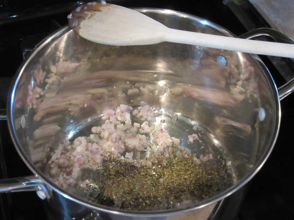Minced shallots and dried herbs in a large saucepan for making sauce.
