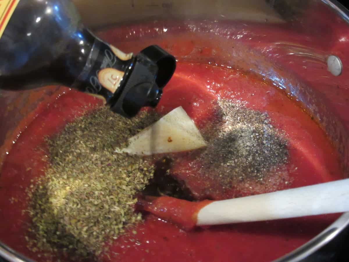 Worcestershire sauce being added to a saucepan of homemade marinara sauce.