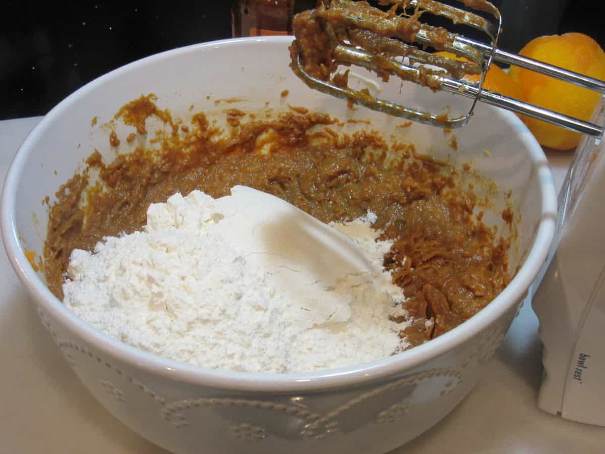 Flour in a white bowl with the wet ingredients for making sweet potato cookies.