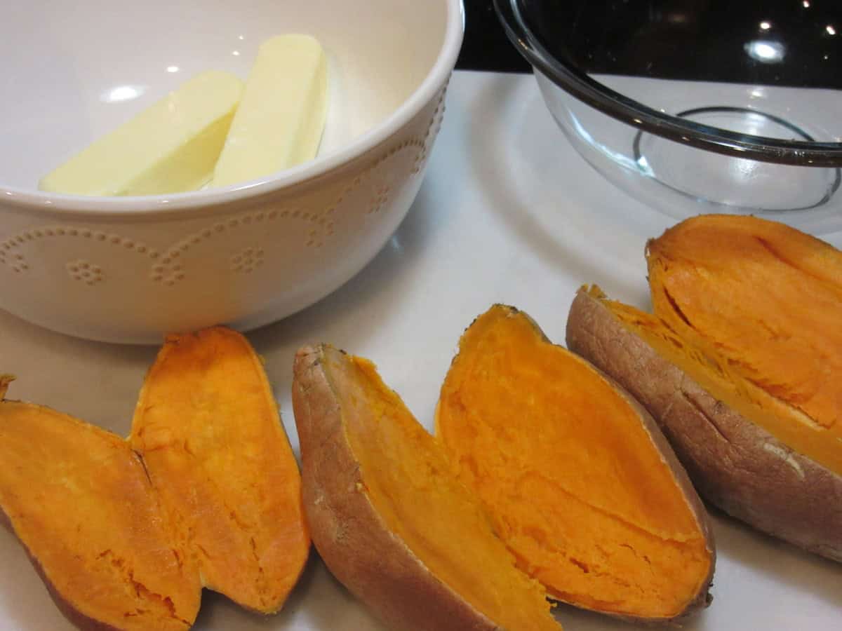 Baked sweet potatoes that have been sliced in half on a countertop.