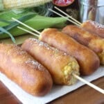 Pancake battered and fried golden corn on the cob fritters topped with powdered sugar.
