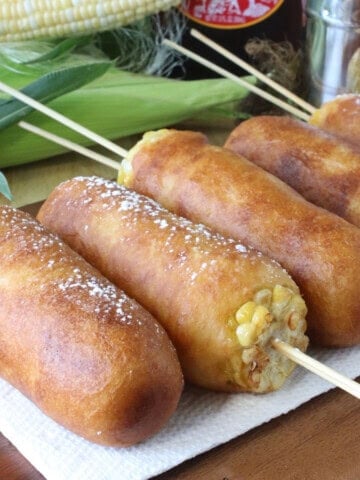 Pancake battered and fried golden corn on the cob fritters topped with powdered sugar.