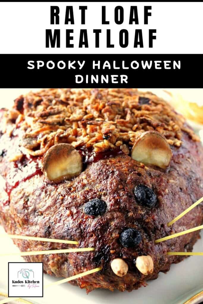 A full face view if a baked and creepy looking rat loaf meatloaf with olive eyes and spaghetti whiskers.