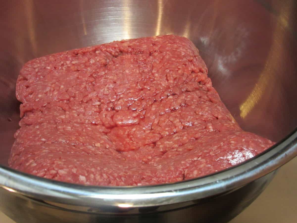 A few pounds of ground beef in a large silver bowl before being made into meatloaf.