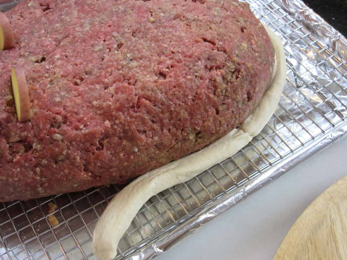 An long unbaked bread biscuit tail for a rat loaf meatloaf.