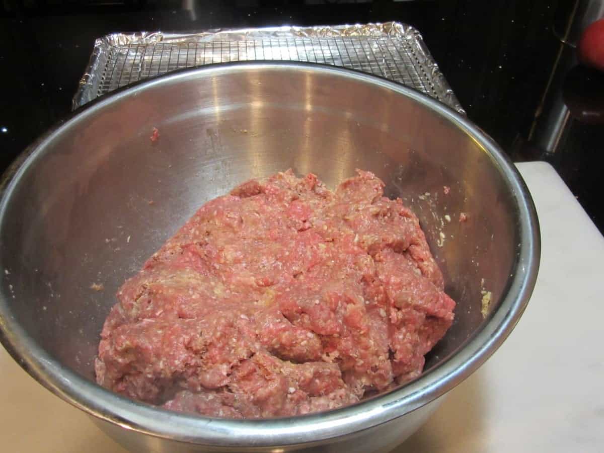 A blend of ground beef and and pork in a large silver bowl.