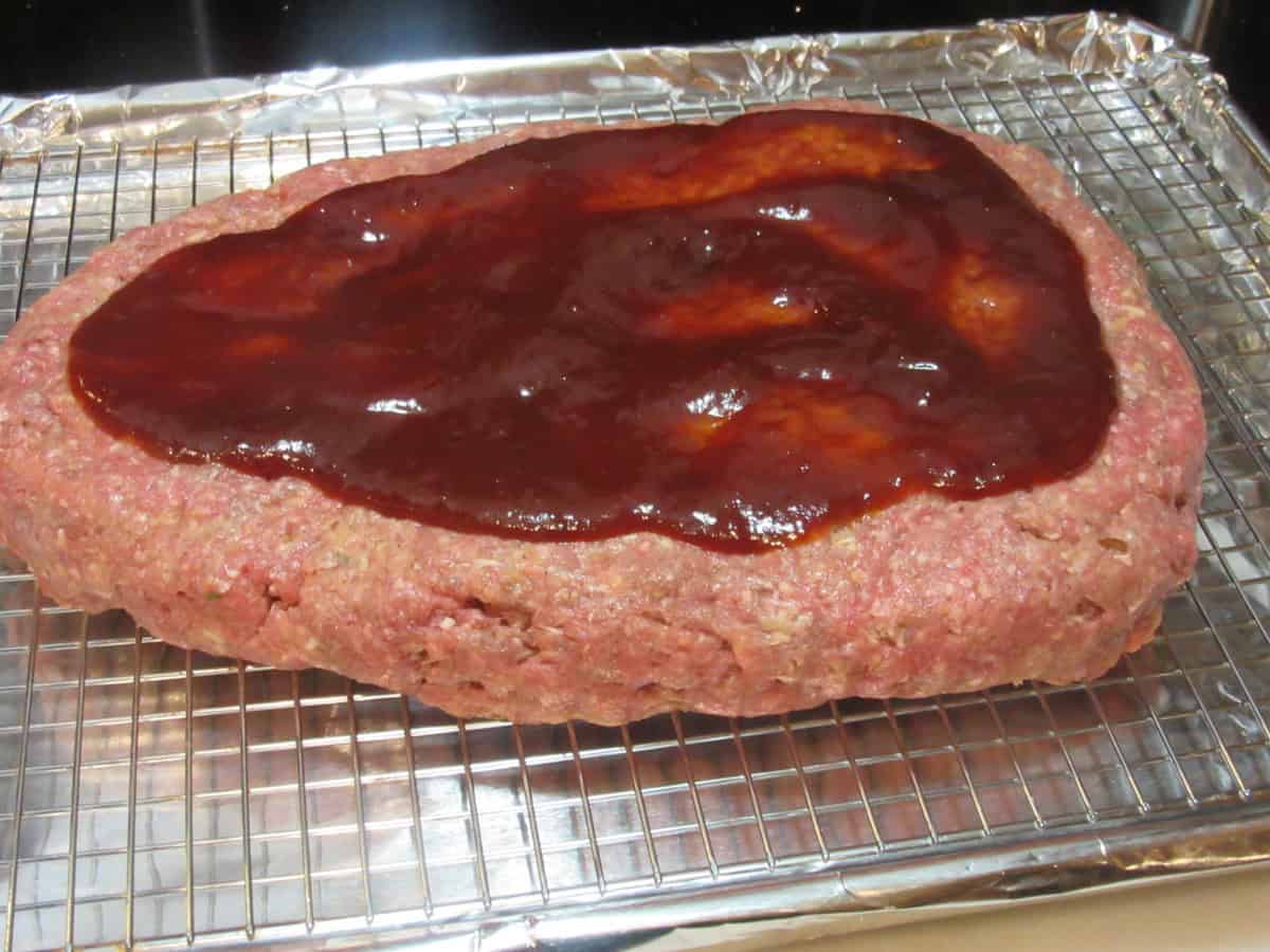 BBQ sauce spread onto a layer of unbaked meatloaf.