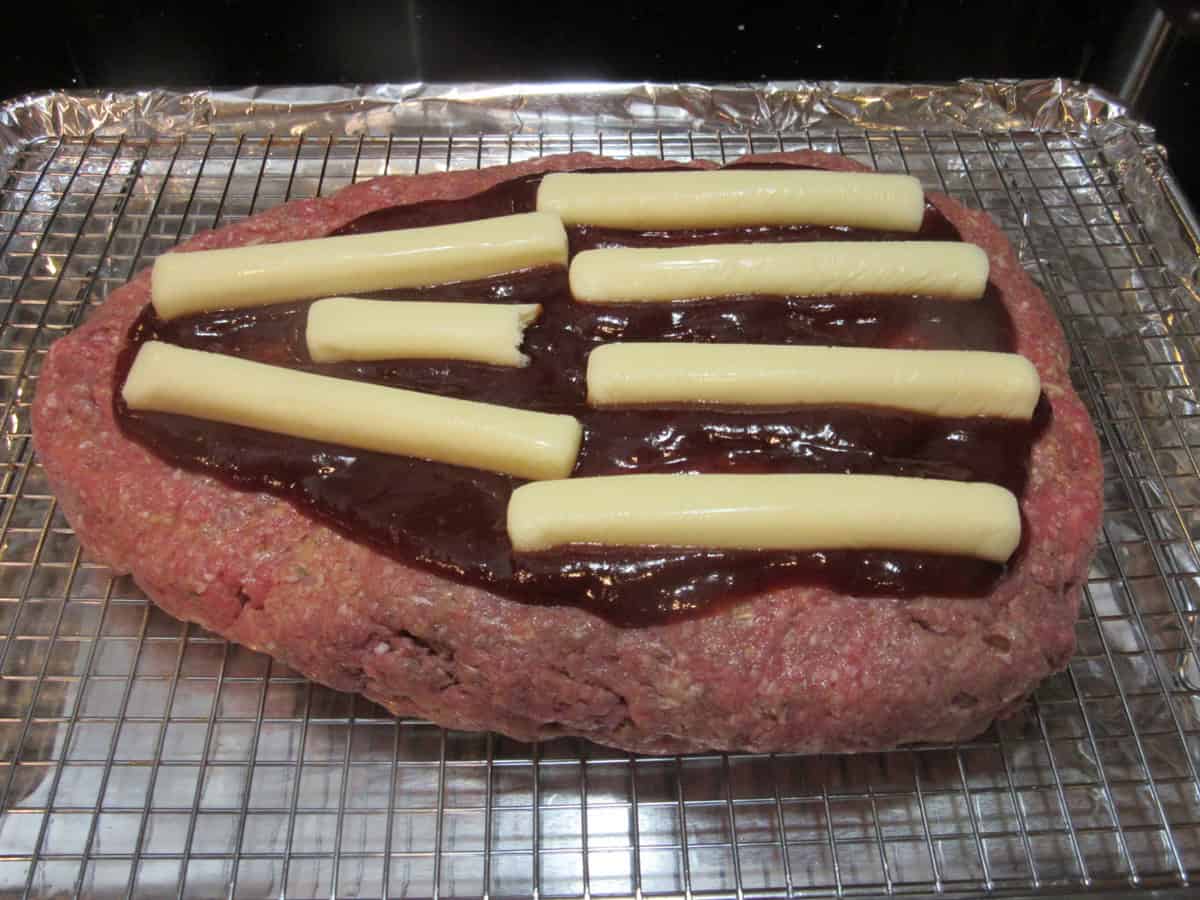 BBQ sauce and string cheese on top of a bottom layer of meatloaf to make a stuffed meatloaf.