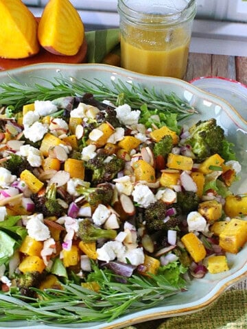 A colorful and fresh looking roasted golden beet and broccoli salad topped with almonds and goat cheese.