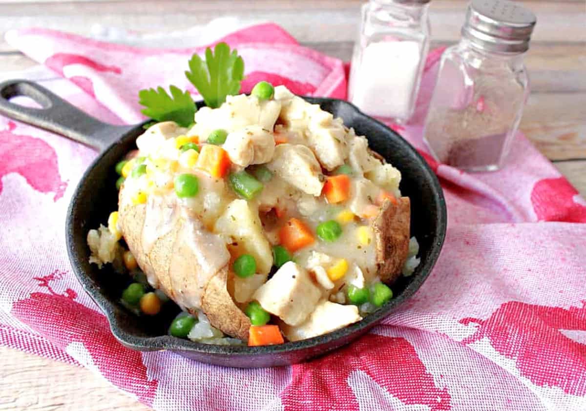 A small cast iron skillet with a creamy chicken pot potato inside.