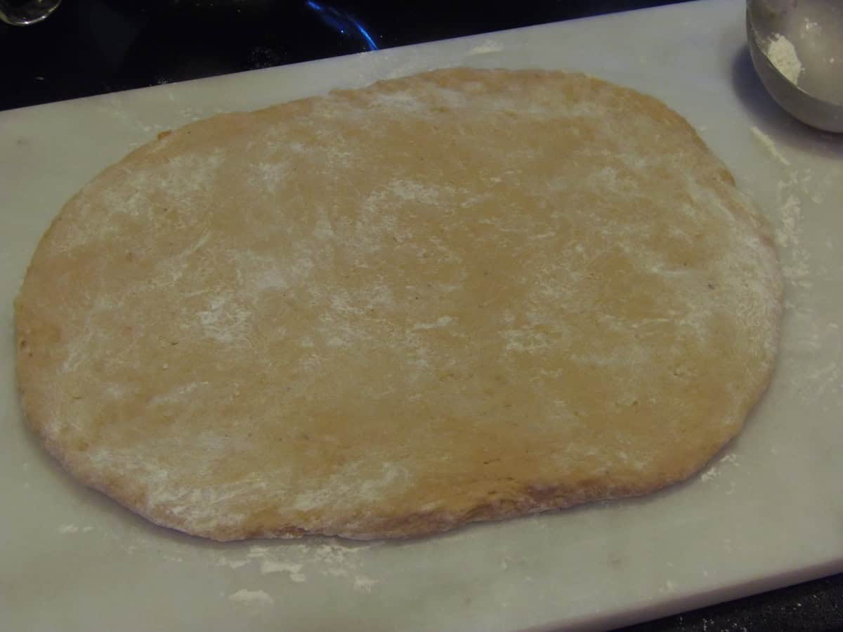 A rolled out slab of sweet potato donut dough on a floured surface.