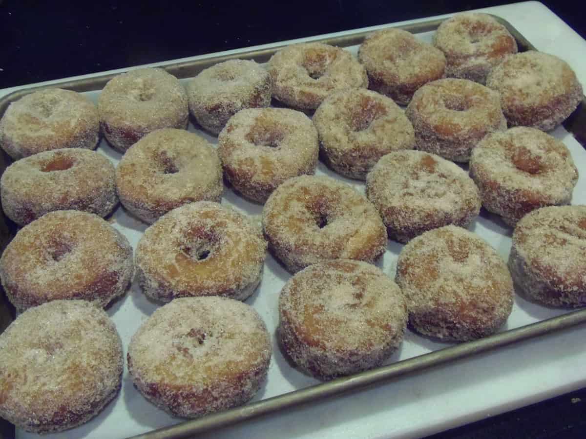 A baking sheet filled with cinnamon sugar topped Sweet Potato Cake Donuts.