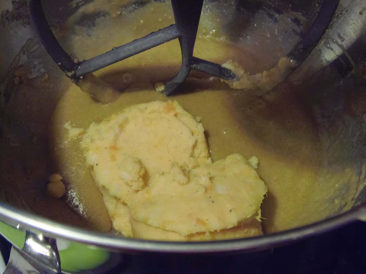 Mashed sweet potatoes inside a stand mixer bowl along with wet ingredients.