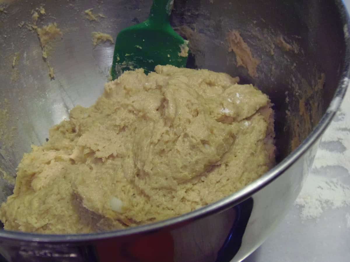 A soft doughnut dough in a stand mixer bowl with a silicone spatula.