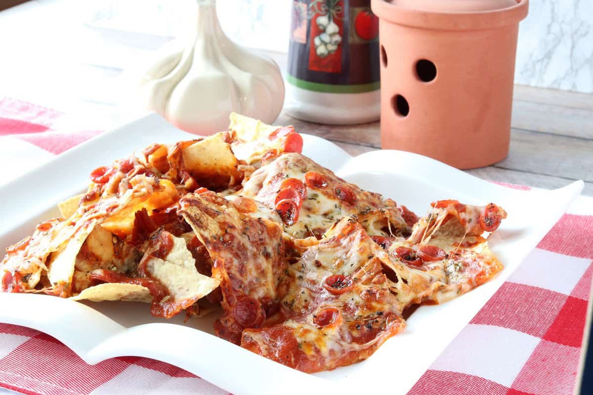 An Italian-inspired table setting for pizza nachos with melted cheese and pepperoni on a serving platter.