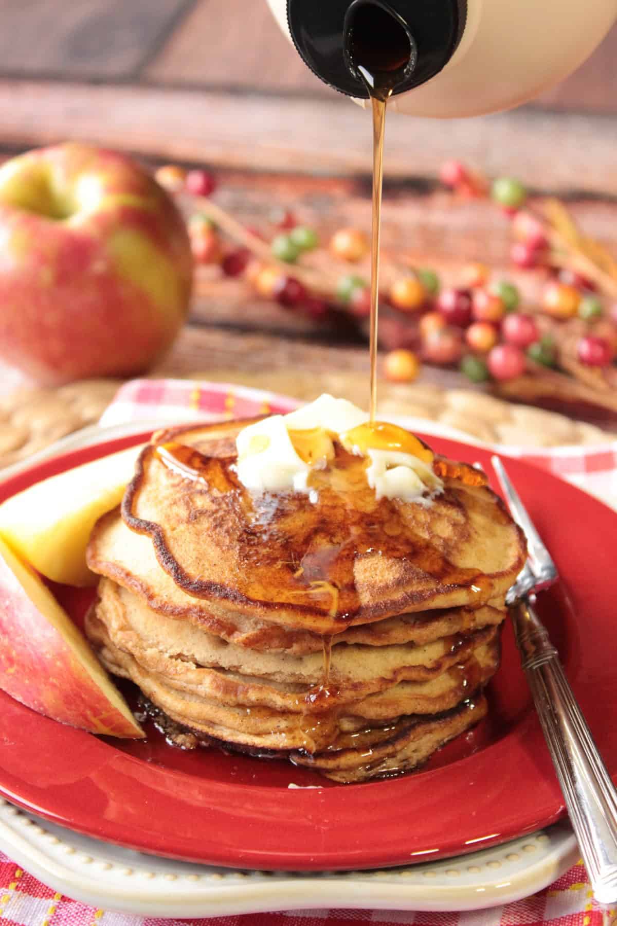 Apple Cider Pancakes - www.kudoskitchenbyrenee.com Syrup being poured onto a stack of apple cider pancakes.