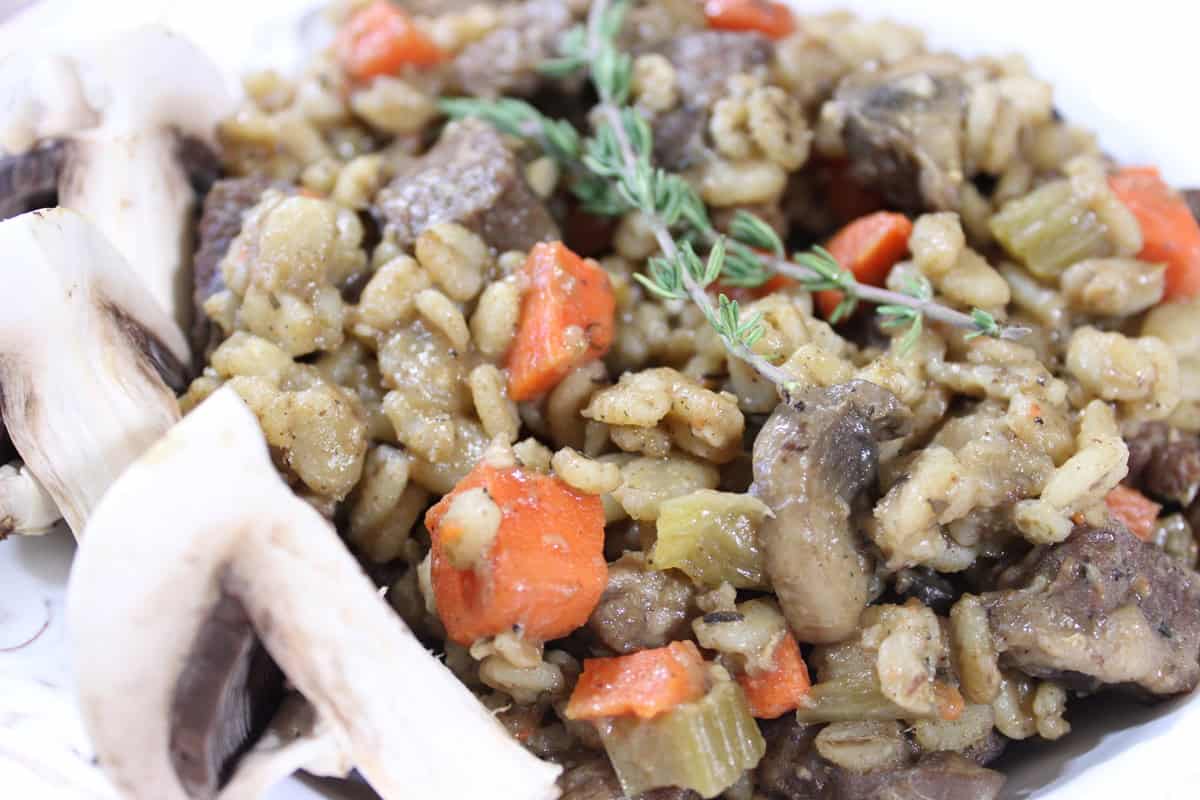 Beef barley mushroom stew is as good tasting as it is good for you - Kudos Kitchen by Renee Cooked beef, barley and mushroom stew with carrots and fresh thyme on top.