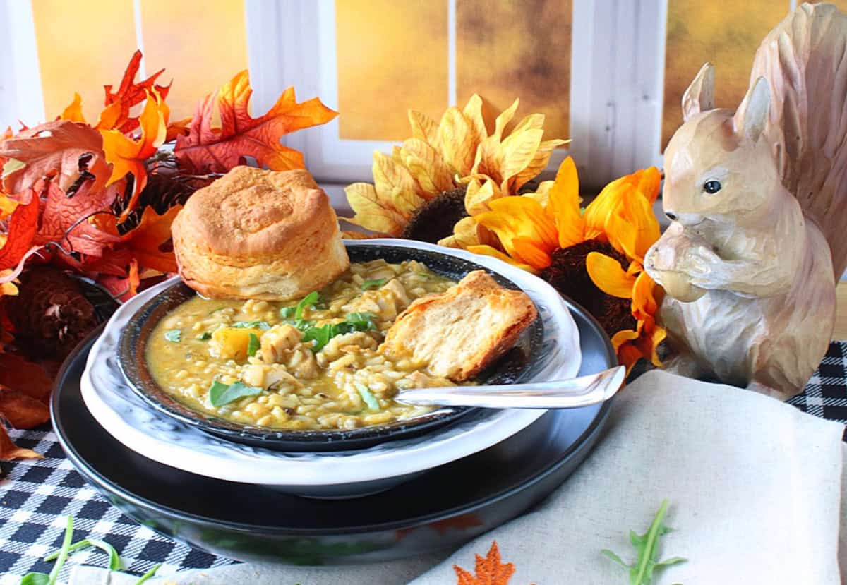 A fall background is set for a bowl of chicken and wild rice soup with butternut squash.