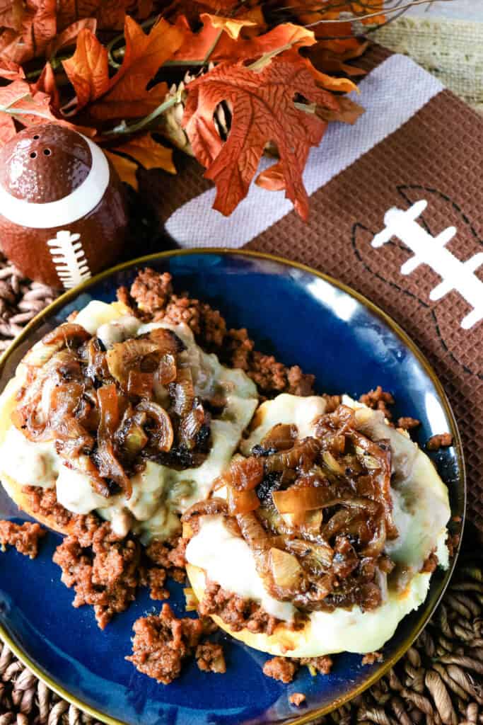 French onion sloppy joe sandwich on a blue plate with a football and fall theme.