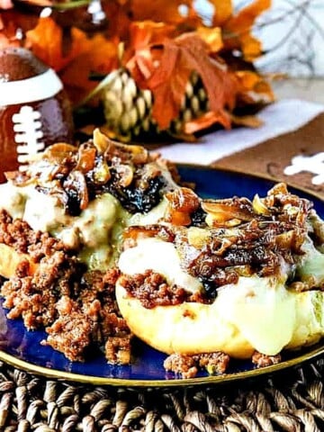 An open face French onion sloppy Joe sandwich topped with melted cheese and caramelized onions.