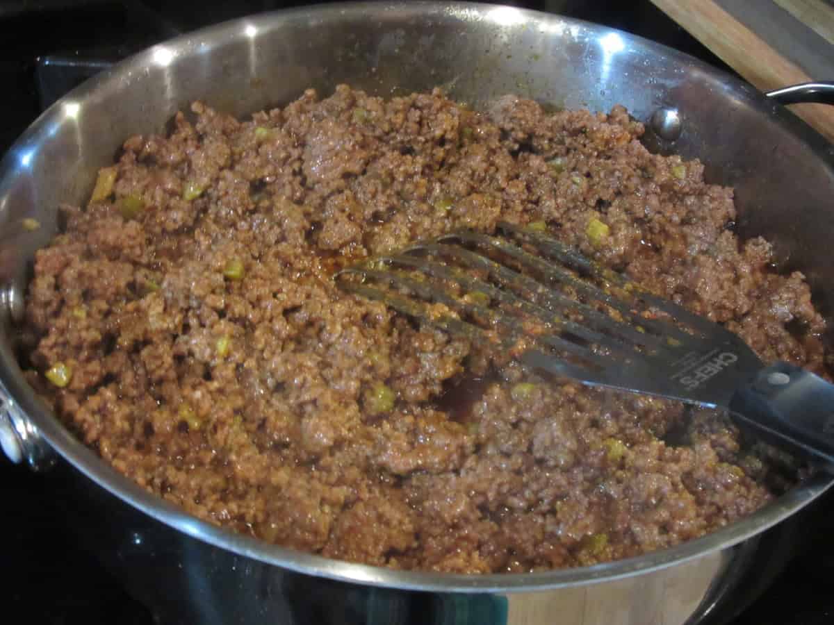 Cooked sloppy joe mix of ground beef and cooked celery in a large skillet on the stovetop.