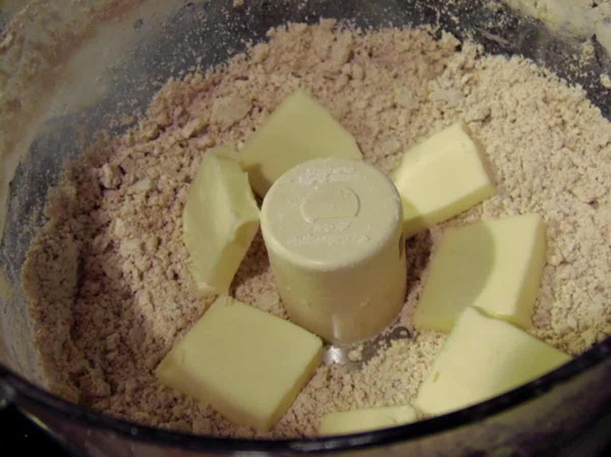 Butter and flour inside the bowl of a food processor to make crackers.
