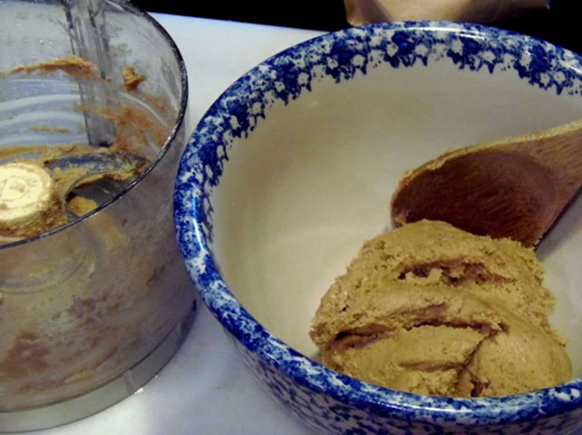 A brown cracker in a bowl with a wooden spoon.