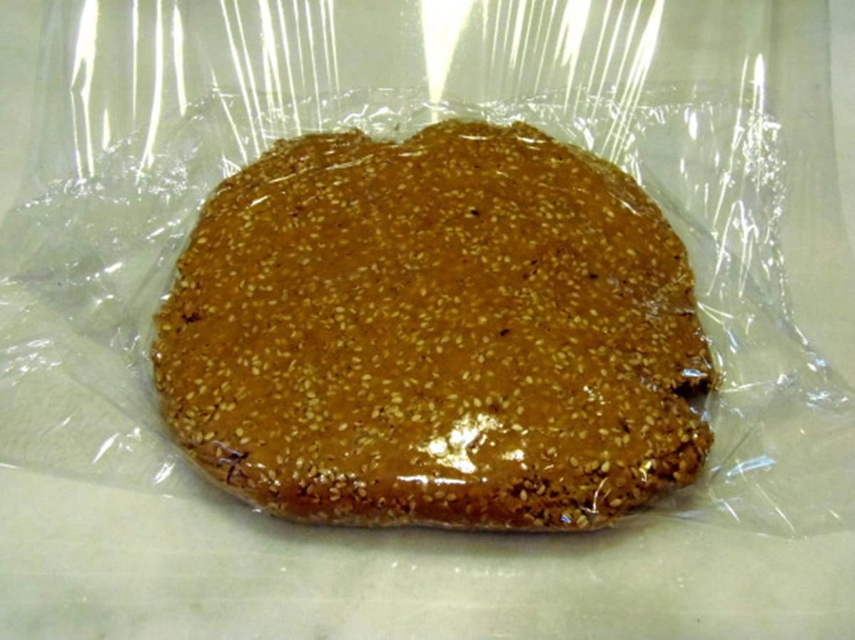 Sesame seed cracker dough wrapped in plastic wrap for chilling.