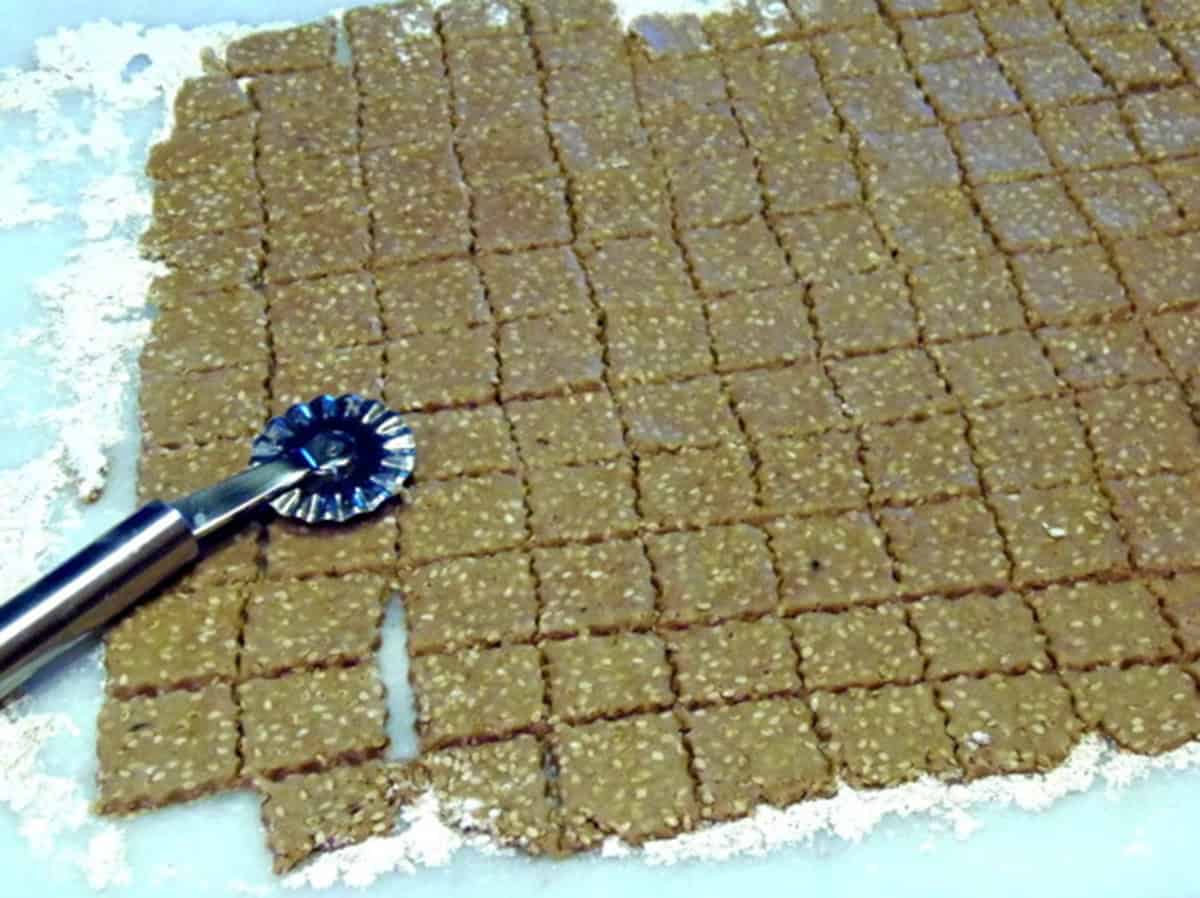 A crimper cutter on sesame seed dough for making crackers.