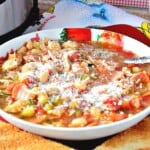 Grated cheese on top of a comforting bowl of Italian soup with chicken and pepperoni.