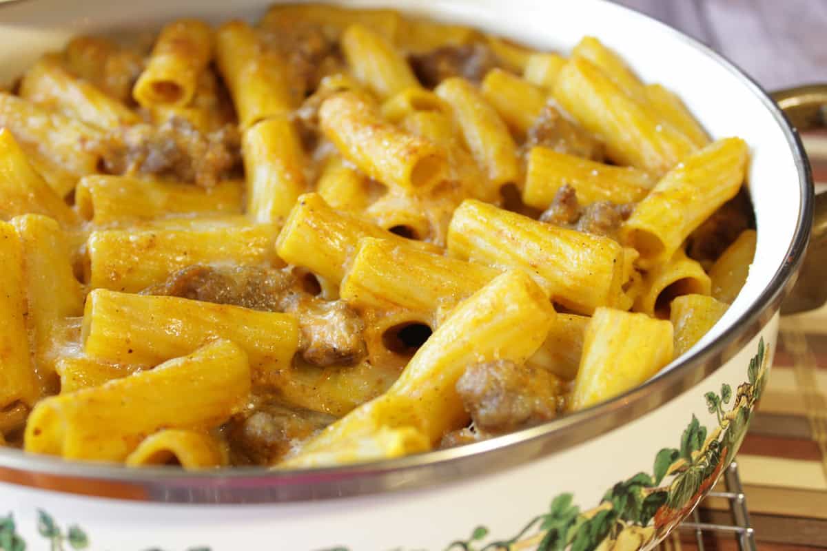 Baked rigatoni with pumpkin cream sauce and bratwurst in a casserole dish.