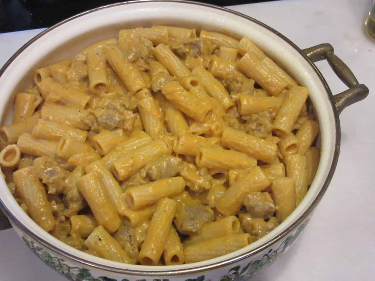 Creamy pumpkin pasta with bratwurst in a casserole dish before baking.
