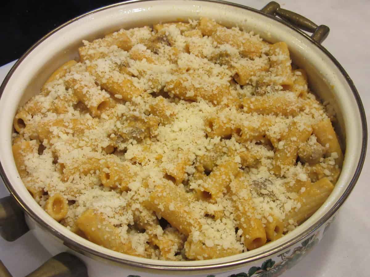 Grated Parmesan cheese topped pumpkin rigatoni in a casserole dish.