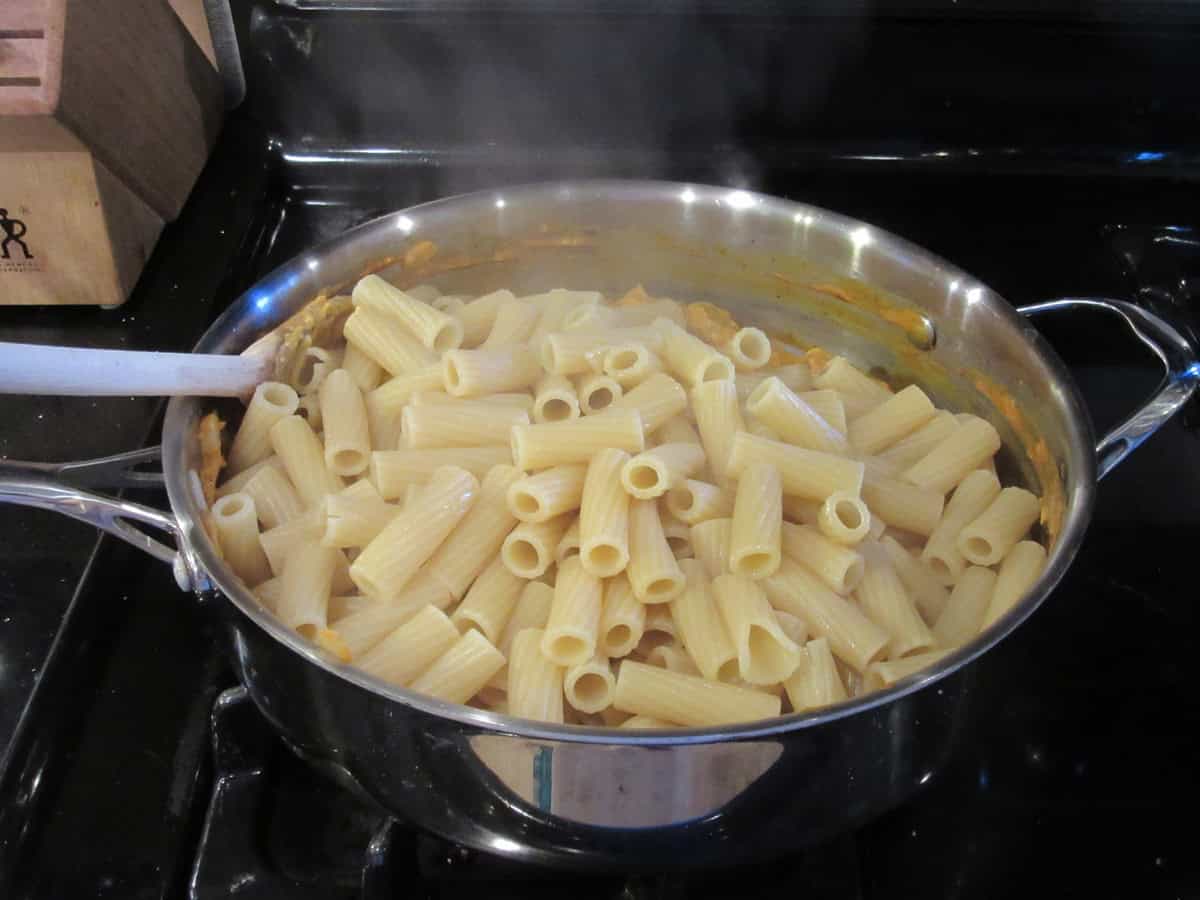 Cooked and drained rigatoni in a large skillet on the stovetop.