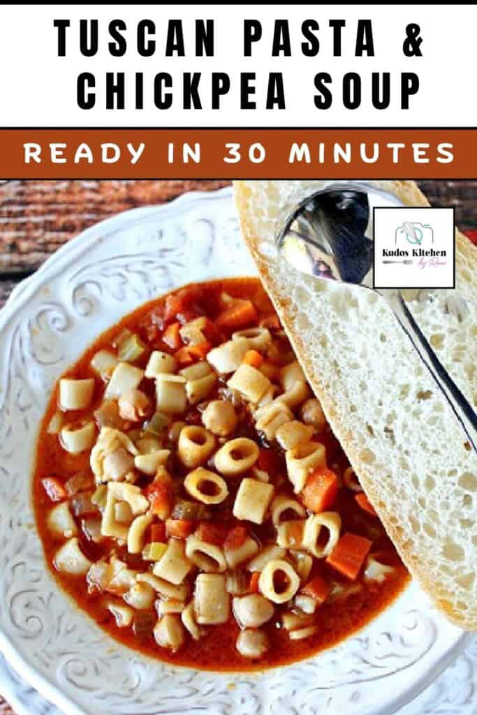 A hearty looking bowl of Tuscan pasta and chick pea soup with carrots and a slice of bread with a spoon.