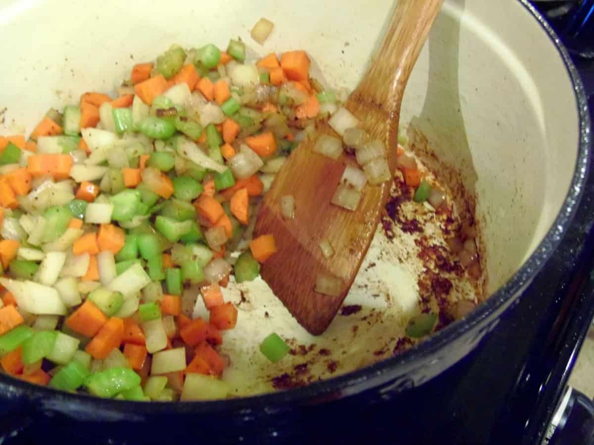 Veggies sauteing in a Dutch oven along with the fond at the bottom of the pot.
