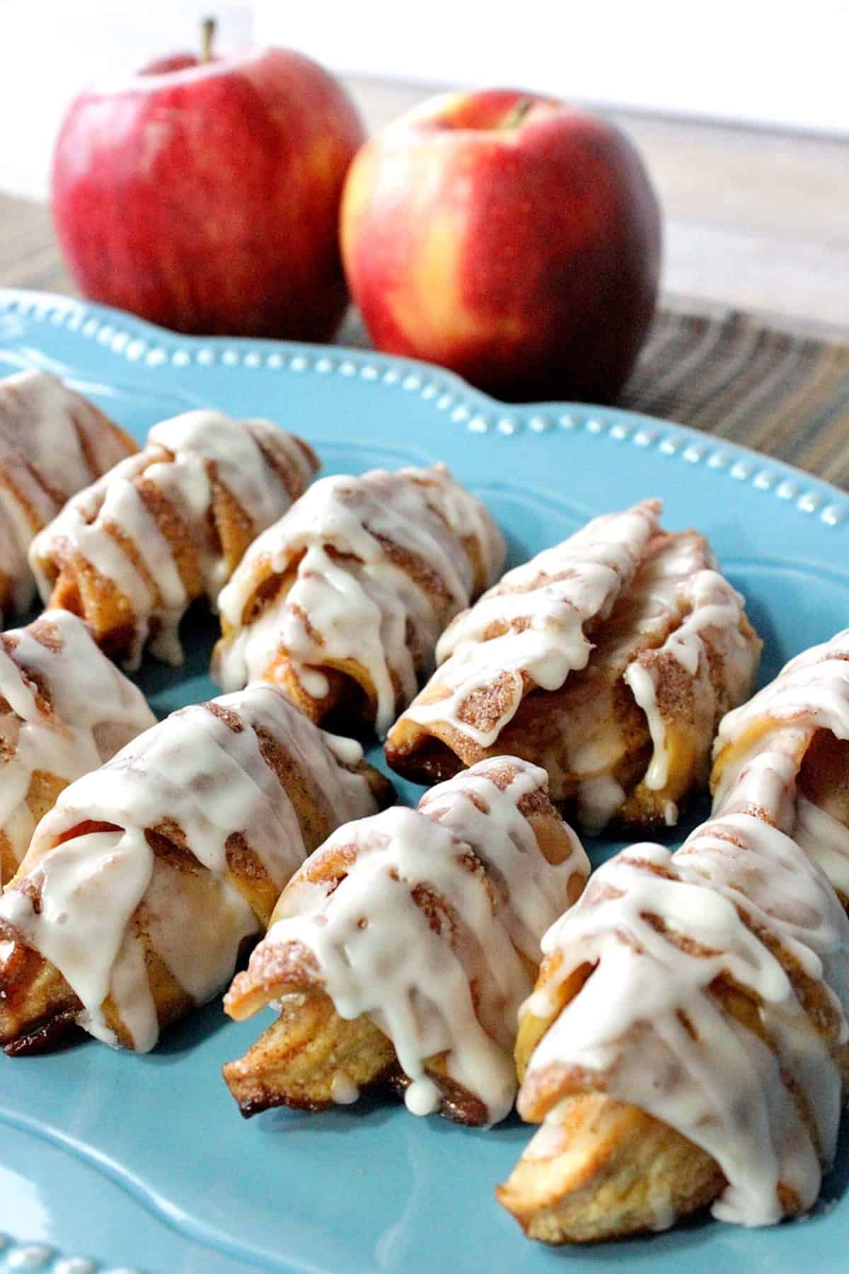 A bright blue platter filled with apple pie wedges covered with glaze.