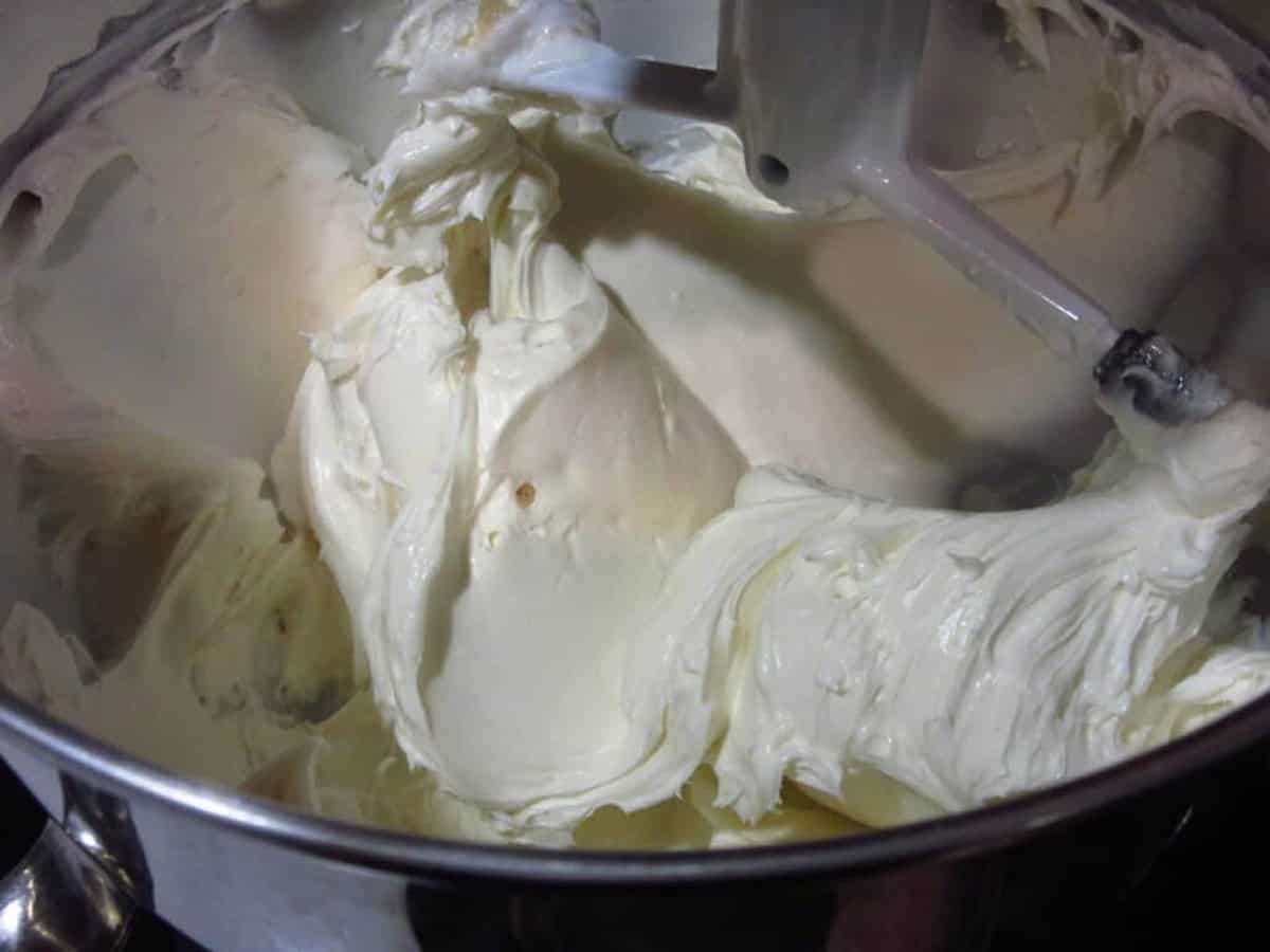 A thick and creamy cheesecake filling in the bowl of a stand mixer.