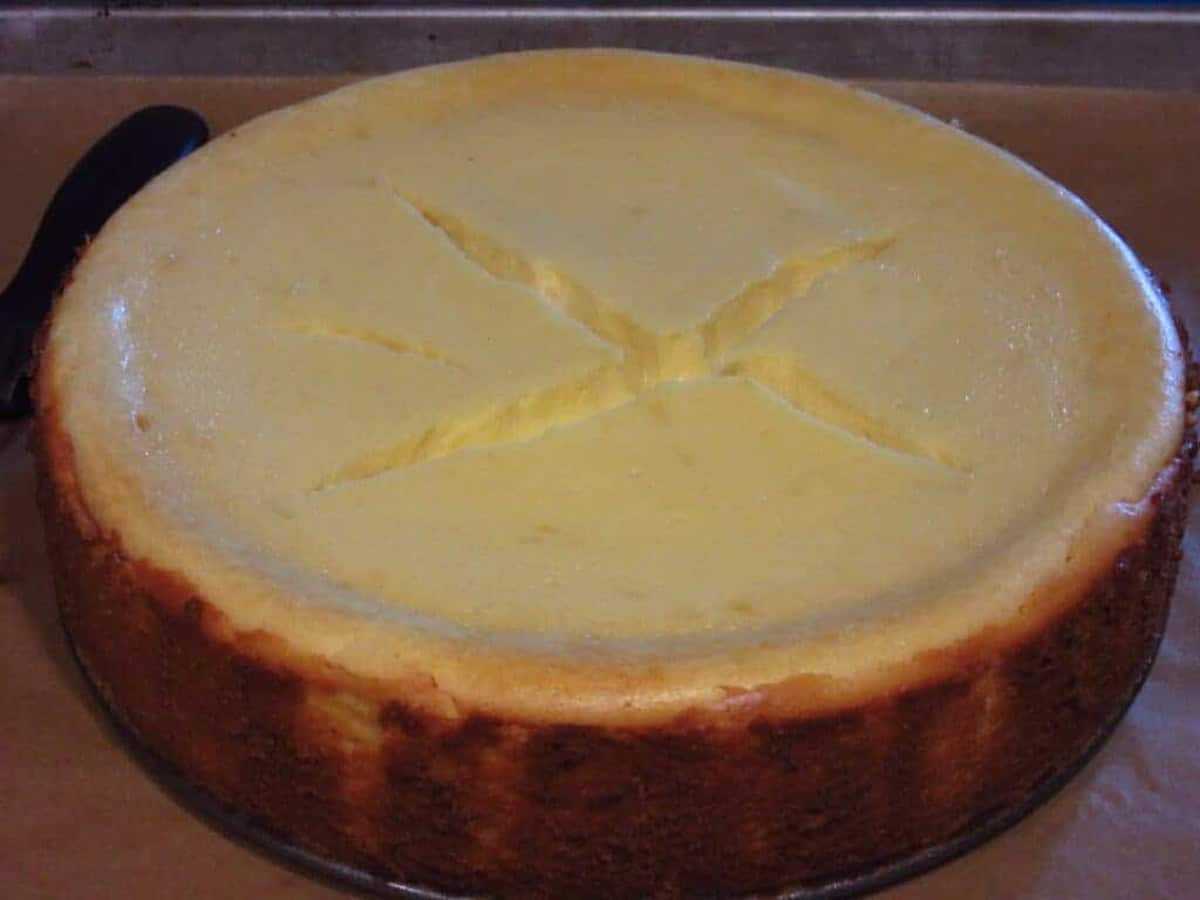 A baked cheesecake with large cracks on the top after baking.