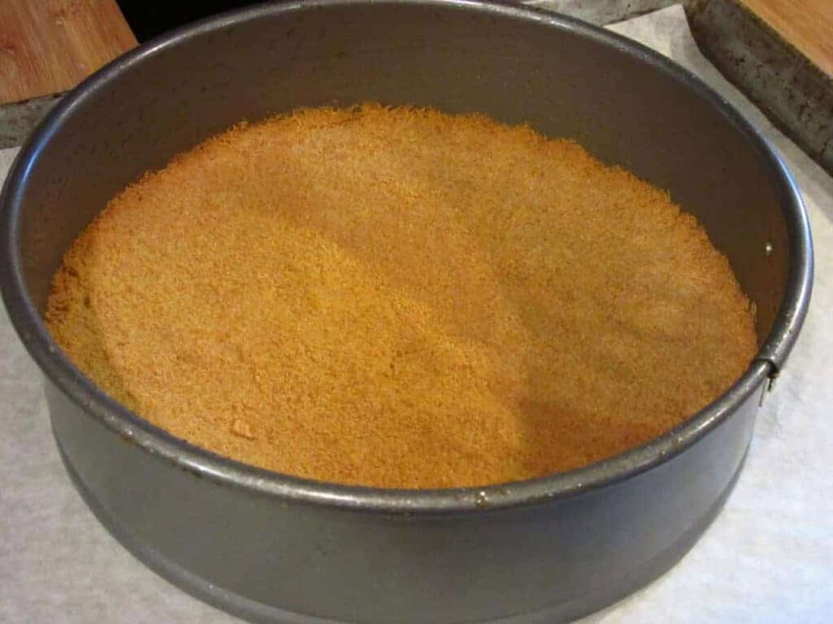 A baked and golden graham cracker crust in the bottom of a springform pan.