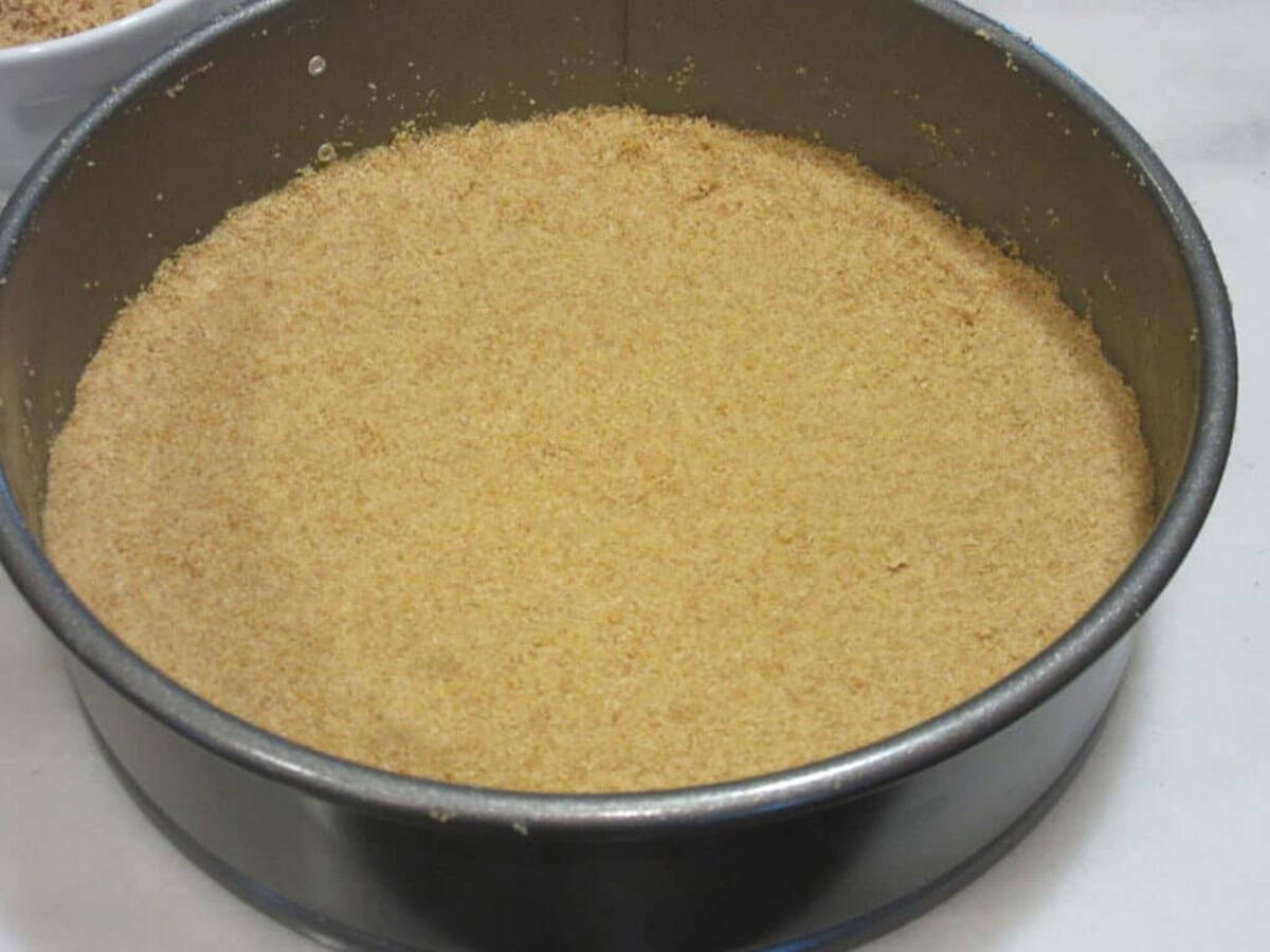 Flattened graham cracker crust in a springform pan before baking.