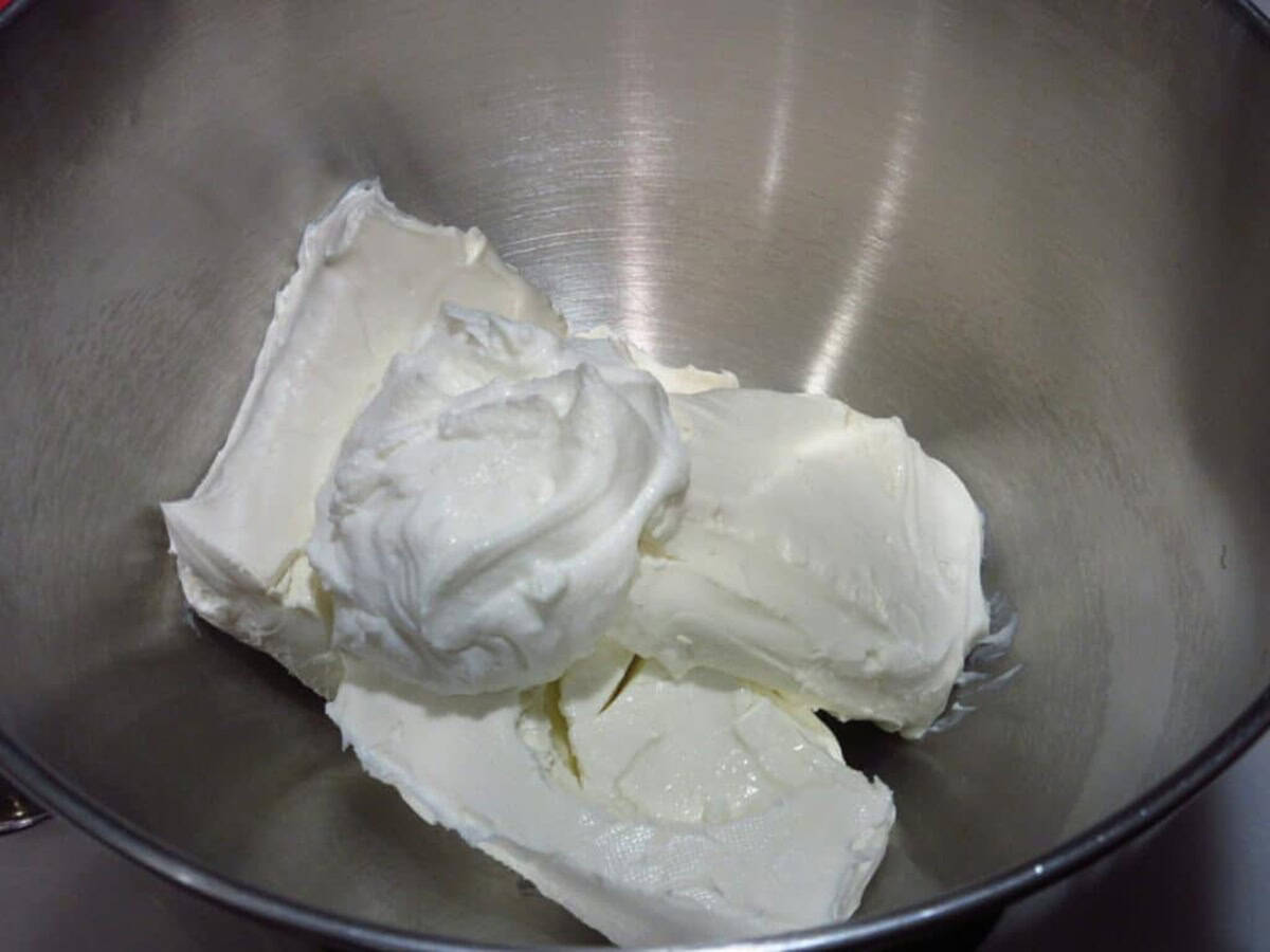 Softened cream cheese blocks and sour cream in a silver bowl.