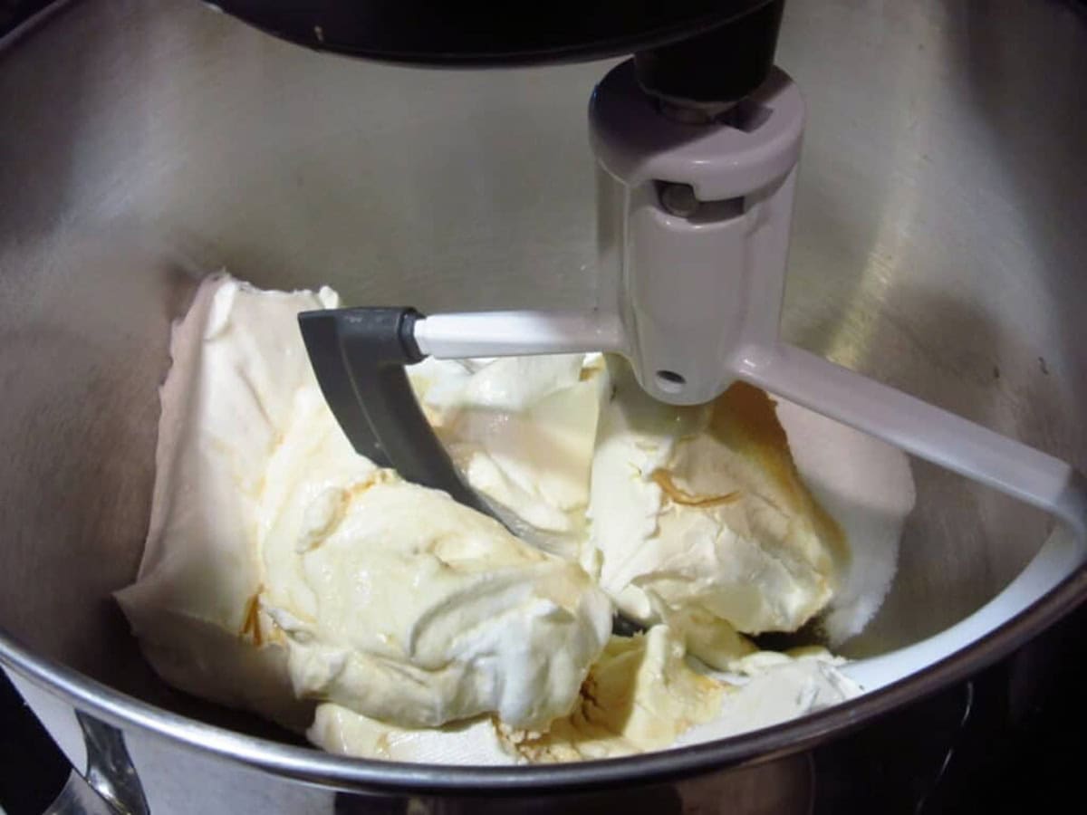 Cream cheese blocks and sugar before mixing in the bowl of a stand mixer.